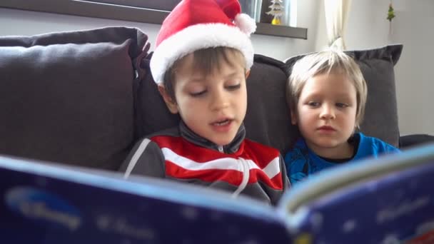 Hermanos hermosa lectura de un cuento, el día de Navidad — Vídeos de Stock