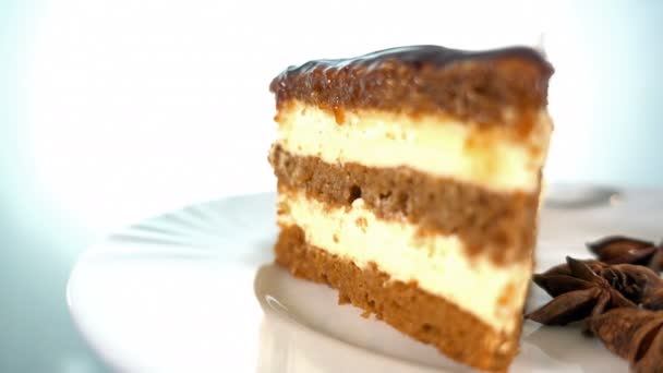 Fatia de bolo de chocolate num prato branco, rotação, 4K contra — Vídeo de Stock