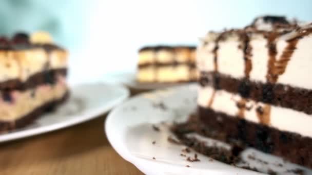 Різні скибочки тортів на білих тарілках, що обертаються, кулачок з низьким кутом, 4K — стокове відео