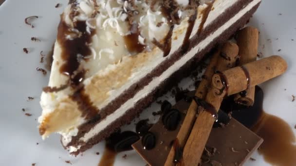 Plasterek ciasta czekoladowe z czekoladą i cynamonem na biały talerz obrotowy, 4k — Wideo stockowe