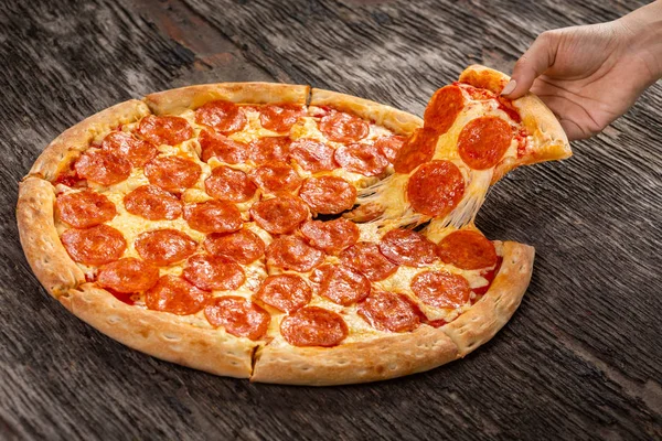 Sıcak biberli pizza yemeye hazır. Eski ahşap masanın üzerinde çok ucuz bir pizza dilimi.
