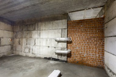 Büyük bir binanın bodrumunun beton yapısı. Zemin kat modern inşaat alanının içinde floresan ve doğal ışıkların karışımı. Çağdaş yapı beton ve tuğlalar duvarlar, sütunlar, tavan ve zemin