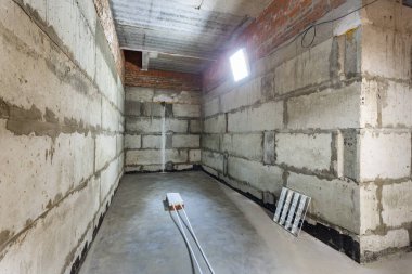 Büyük bir binanın bodrumunun beton yapısı. Zemin kat modern inşaat alanının içinde floresan ve doğal ışıkların karışımı. Çağdaş yapı beton ve tuğlalar duvarlar, sütunlar, tavan ve zemin