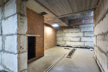 Büyük bir binanın bodrumunun beton yapısı. Zemin kat modern inşaat alanının içinde floresan ve doğal ışıkların karışımı. Çağdaş yapı beton ve tuğlalar duvarlar, sütunlar, tavan ve zemin