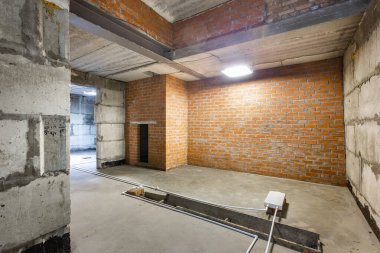 Büyük bir binanın bodrumunun beton yapısı. Zemin kat modern inşaat alanının içinde floresan ve doğal ışıkların karışımı. Çağdaş yapı beton ve tuğlalar duvarlar, sütunlar, tavan ve zemin