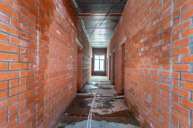 Büyük bir binanın bodrumunun beton yapısı. Zemin kat modern inşaat alanının içinde floresan ve doğal ışıkların karışımı. Çağdaş yapı beton ve tuğlalar duvarlar, sütunlar, tavan ve zemin