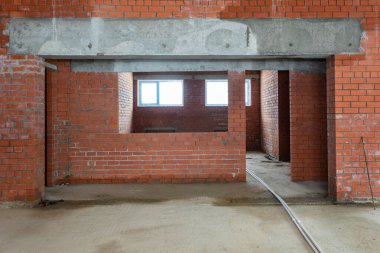 Büyük bir binanın bodrumunun beton yapısı. Zemin kat modern inşaat alanının içinde floresan ve doğal ışıkların karışımı. Çağdaş yapı beton ve tuğlalar duvarlar, sütunlar, tavan ve zemin
