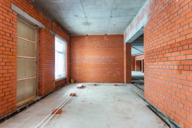 Büyük bir binanın bodrumunun beton yapısı. Zemin kat modern inşaat alanının içinde floresan ve doğal ışıkların karışımı. Çağdaş yapı beton ve tuğlalar duvarlar, sütunlar, tavan ve zemin