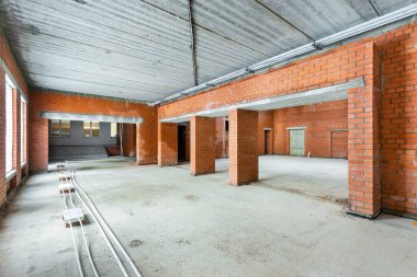 Büyük bir binanın bodrumunun beton yapısı. Zemin kat modern inşaat alanının içinde floresan ve doğal ışıkların karışımı. Çağdaş yapı beton ve tuğlalar duvarlar, sütunlar, tavan ve zemin