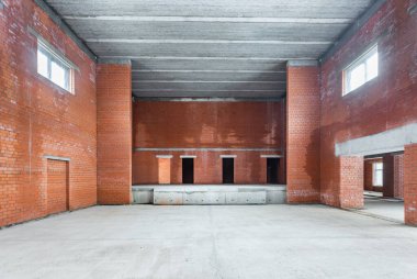 Büyük bir binanın bodrumunun beton yapısı. Zemin kat modern inşaat alanının içinde floresan ve doğal ışıkların karışımı. Çağdaş yapı beton ve tuğlalar duvarlar, sütunlar, tavan ve zemin