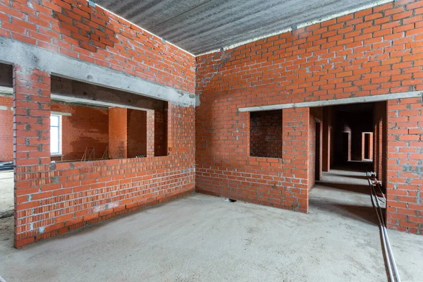 Büyük bir binanın bodrumunun beton yapısı. Zemin kat modern inşaat alanının içinde floresan ve doğal ışıkların karışımı. Çağdaş yapı beton ve tuğlalar duvarlar, sütunlar, tavan ve zemin