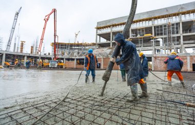 Togliatti, Samara Oblastı / Rusya - 12 Ekim 2011: Beton pompa inşaat alanında beton taşır. Endüstriyel işçiler temelleri döker ve özel aletlerle yerle bir ederler.