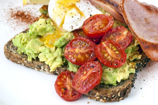 Avocado-Toast mit Kirschtomaten pochiertes Ei und Speck top vie — Stockfoto