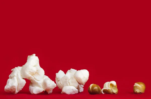Popcorn su sfondo rosso vibrante kernel poppati e non poppati — Foto Stock