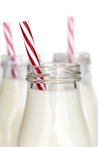 Bottiglie di latte con cannucce a strisce rosse su bianco — Foto Stock