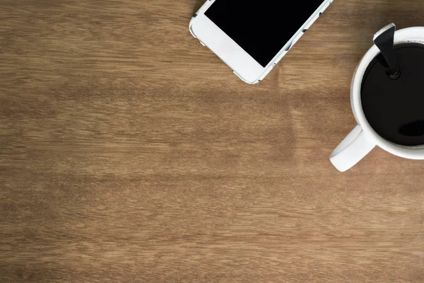 Xícara de café e Smartphone na vista superior de mesa de madeira — Fotografia de Stock