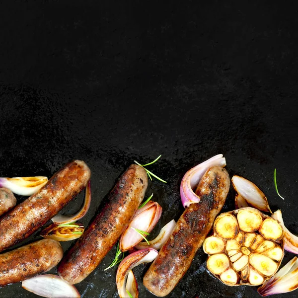 Saucisses grillées avec oignon et ail vue de dessus sur plaque de barbecue — Photo