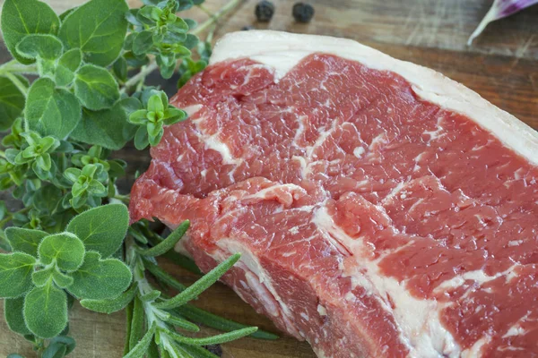 Rohes Rindersteak mit frischen Kräutern an Bord — Stockfoto