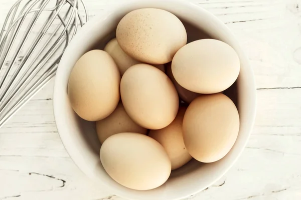 Eieren in de kom met een garde bovenaanzicht — Stockfoto