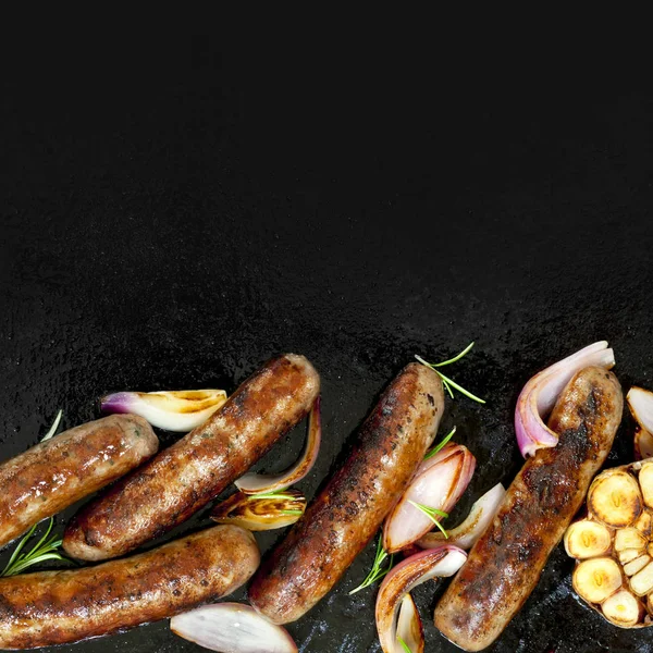 Salsicce alla griglia con cipolla e aglio Top View su piastra barbecue — Foto Stock