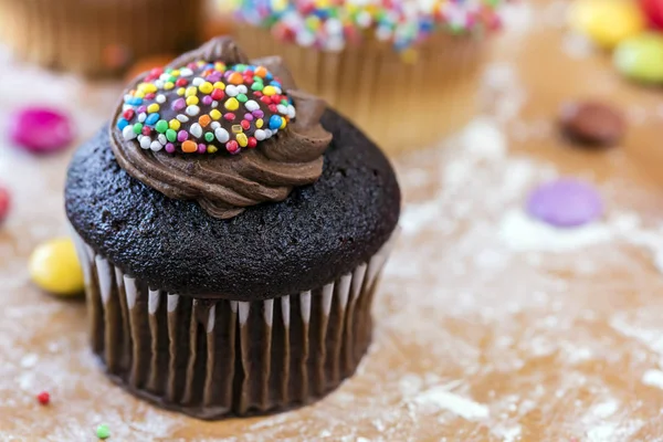 Cupcake al cioccolato con spruzzi su tavola infarinata — Foto Stock