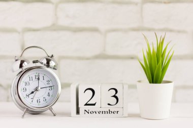 23 Kasım, alarm saatinin yanındaki ahşap takvimde geçen sonbahar ayının takvim tarihi.