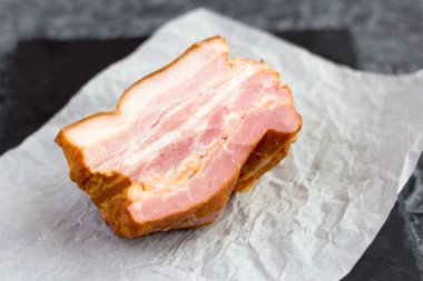 Yumuşak tütsülenmiş domuz pastırması ve masada et parçaları.