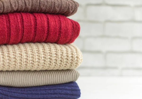 Knitted fluffy sweaters are stacked on a light background — Stock Photo, Image