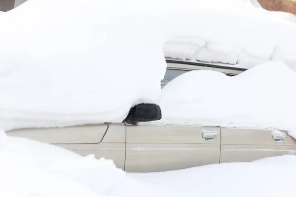 Macchina sotto la neve. Un sacco di neve è caduto sulla strada.L'auto è completamente coperta di neve dopo pesanti nevicate — Foto Stock