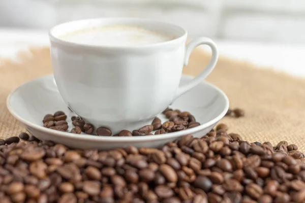 Busa kopi dalam cangkir putih dan biji kopi di atas meja, selektif fokus — Stok Foto