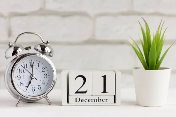 December, alarm clock and calendar on the table.December 21 on a wooden calendar next to the clock
