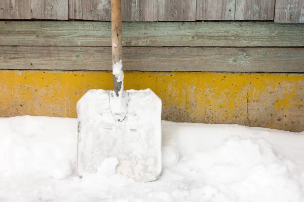 Una grande pala da neve metallica poggia contro il muro — Foto Stock