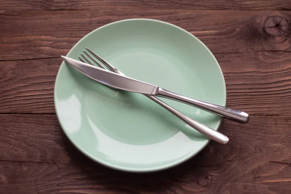 Empty green plate with appliances on a wooden background. — 스톡 사진