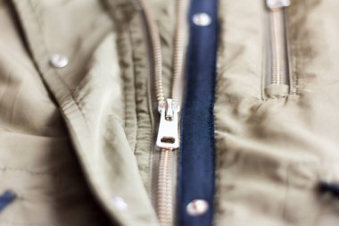 A half-open metal lock on a light khaki jacket.