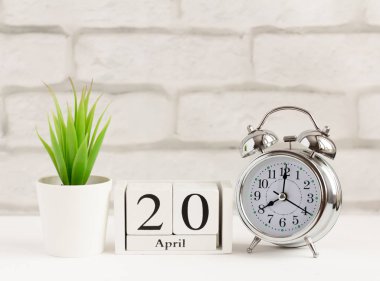 20 Nisan, ahşap takvimde beyaz bir arkaplanda. Saat ve takvim, yılda bir gün kavramı.