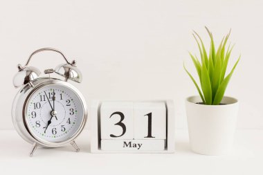 31 Mayıs 'ta ahşap bir takvimde çalar saat ve çiçeğin yanında. Bahar ayının bir günü, arka planda takvim ve çalar saat. Bahçede bahar. Yılda bir gün konsepti..