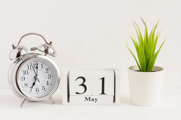 31 Mayıs 'ta ahşap bir takvimde çalar saat ve çiçeğin yanında. Bahar ayının bir günü, arka planda takvim ve çalar saat. Bahçede bahar. Yılda bir gün konsepti..
