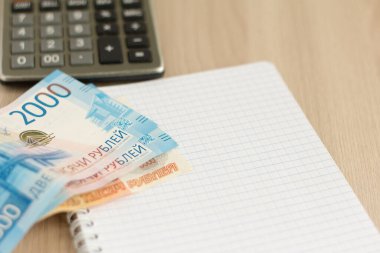 Para. Rus rublesi, hesap makinesi ve masaya yazmak için bir defter. Hesaplama yapma kavramı..