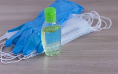 Bir çift lateks tıbbi eldiven, antiviral tıbbi maskeler ve masada bir antiseptik..