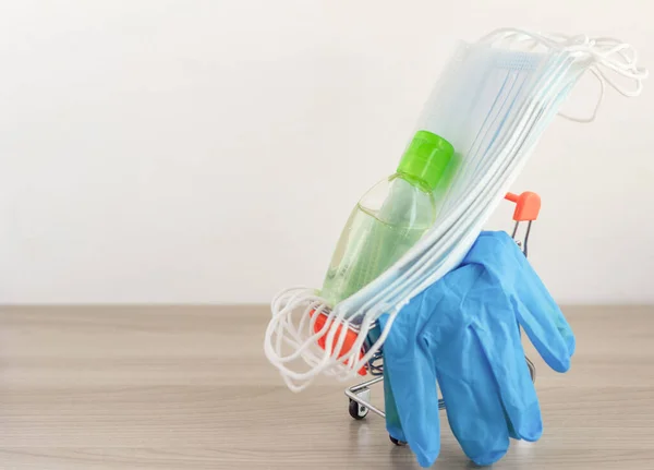 Tıbbi eldivenler, antiviral tıbbi maskeler ve alışveriş arabasında antiseptik. Salgın sırasında markete gitmek için gerekli malzemeler ve aksesuarlar kavramı..