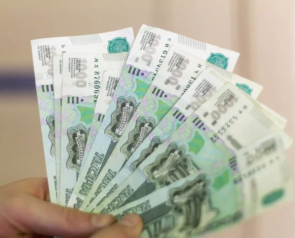Dinero ruso.Un joven sostiene billetes con un valor nominal de 1000 rublos.Mucho dinero en la mano, primer plano . — Foto de Stock