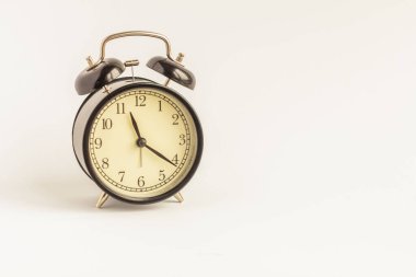 Beyaz zemin üzerinde analog siyah alarm saati.