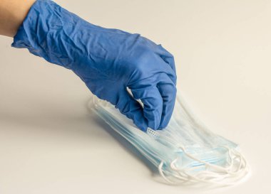 Koruyucu lastik eldivendeki bir el tıbbi bir maske gerektirir. Virüslere ve enfeksiyonlara karşı koruma kavramı.