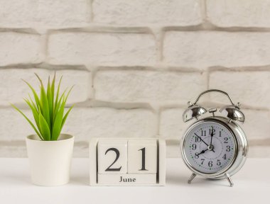 21 Haziran 'da ahşap bir takvimde masanın üzerindeki çalar saatin yanında. Yaz günü, mesaj için boş yer. Takvim tarihi, doğum günü ya da tatil..
