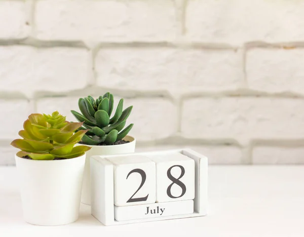 July 28 on a wooden calendar next to it.Calendar date, holiday event, or birthday.One day of the second summer month.