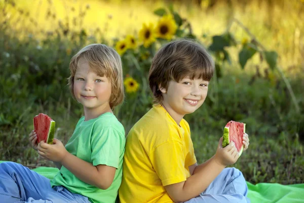 Joyeux enfant mangeant pastèque dans le jardin. Deux garçons avec des fruits dans — Photo