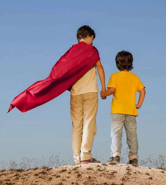 Two boys playing superheroes on the sky background — Stock Photo, Image