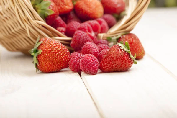 Raspberry and strawberries in a basket on the table in garden — Stock Photo, Image
