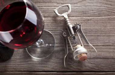 Corkscrew and a glass of wine on an old wooden table clipart