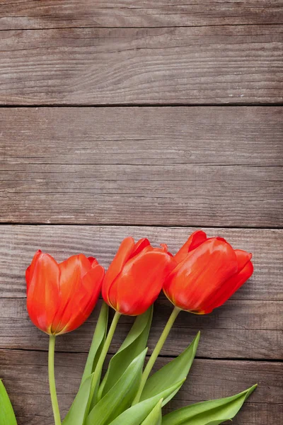 Trzy czerwony tulipan na starych rustykalnych grunge drewna tablica, widok z góry — Zdjęcie stockowe